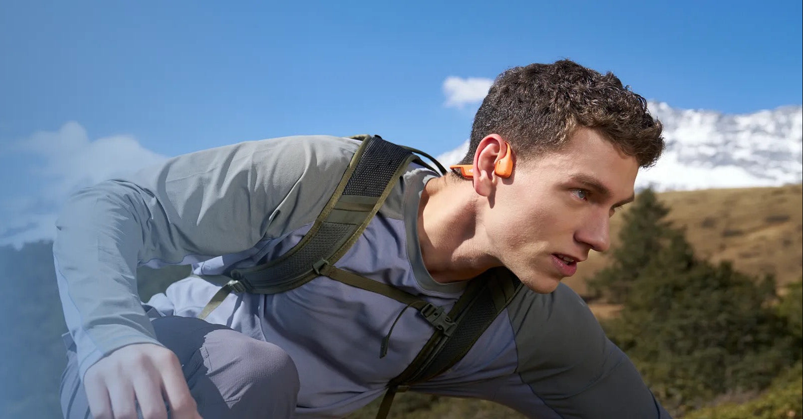 Man hiking with New Real Bone Conduction Sport Headphones with a backpack on a mountain trail