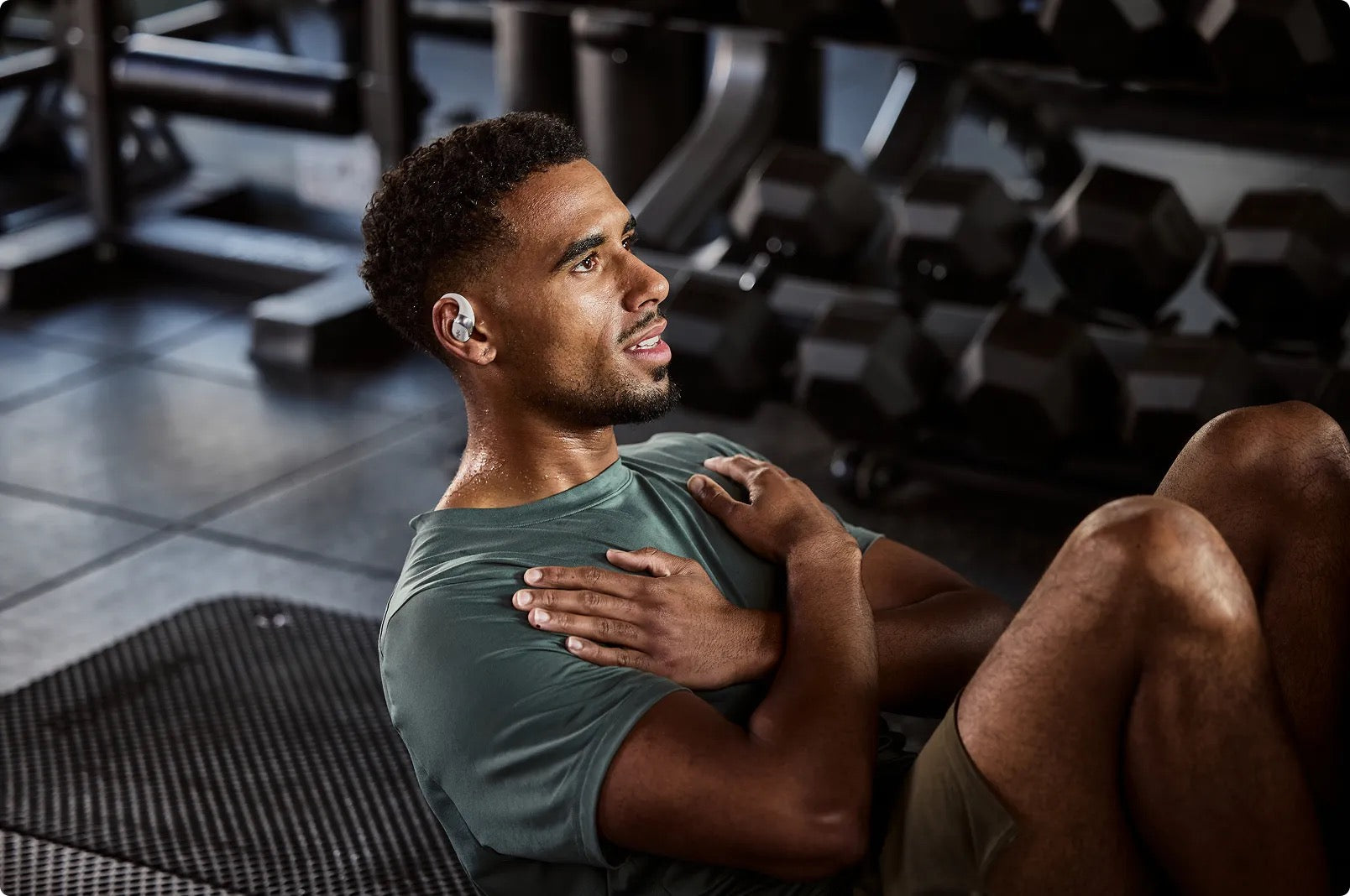 Open Ear Headphones best workout headphones. Man exercising on a mat in a gym setting