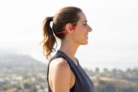 Woman with a ponytail standing outdoors with New Real Bone Conduction Sport Headphones mountains in the background