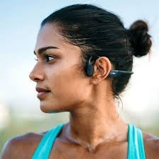 Woman wearing a wireless bone conduction headphone with a blurred natural background