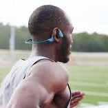 Person running on a track wearing wireless bone conductible headphones